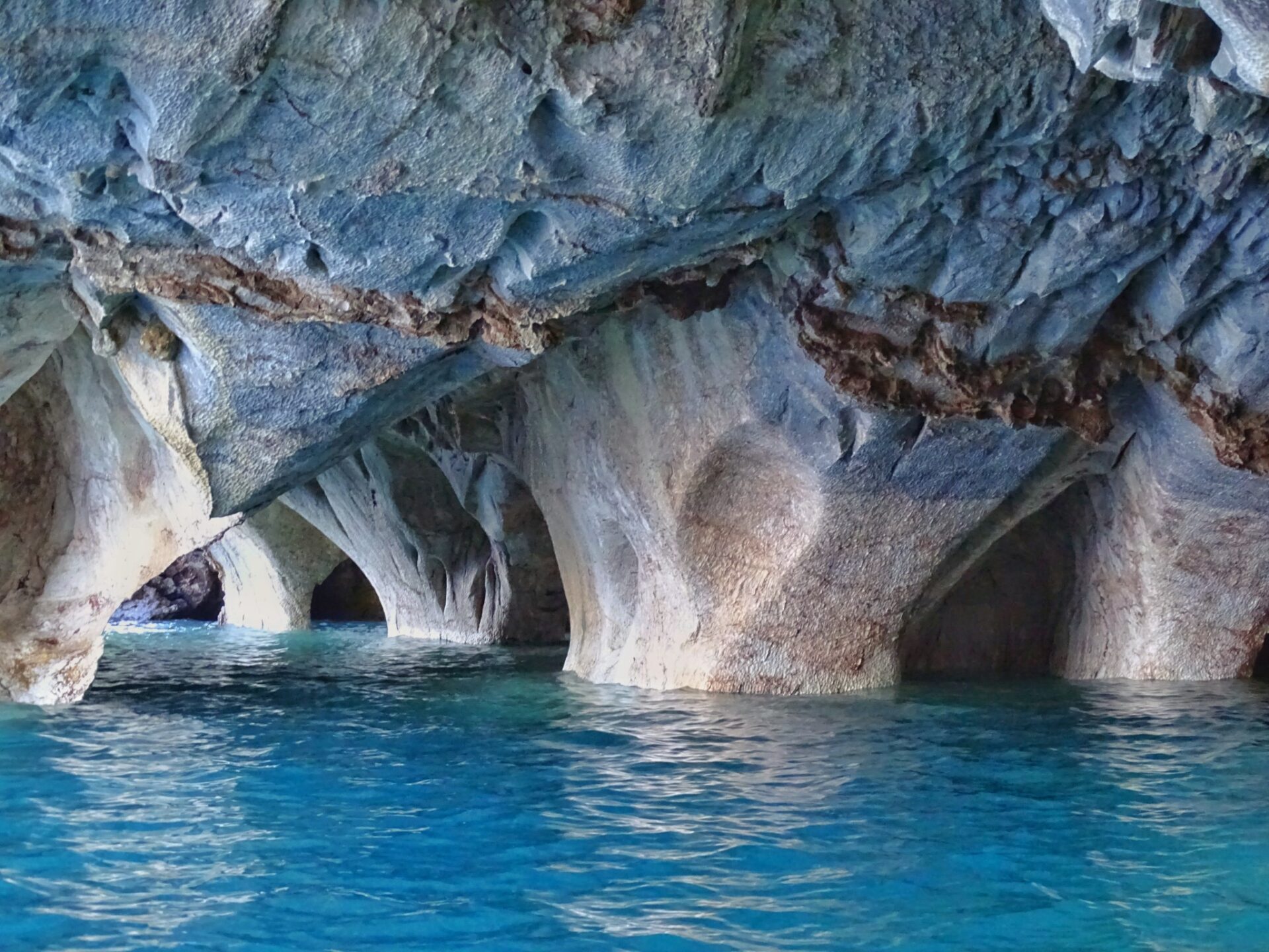 Smooth marble formations reflected in blue water inside the Marble Caves