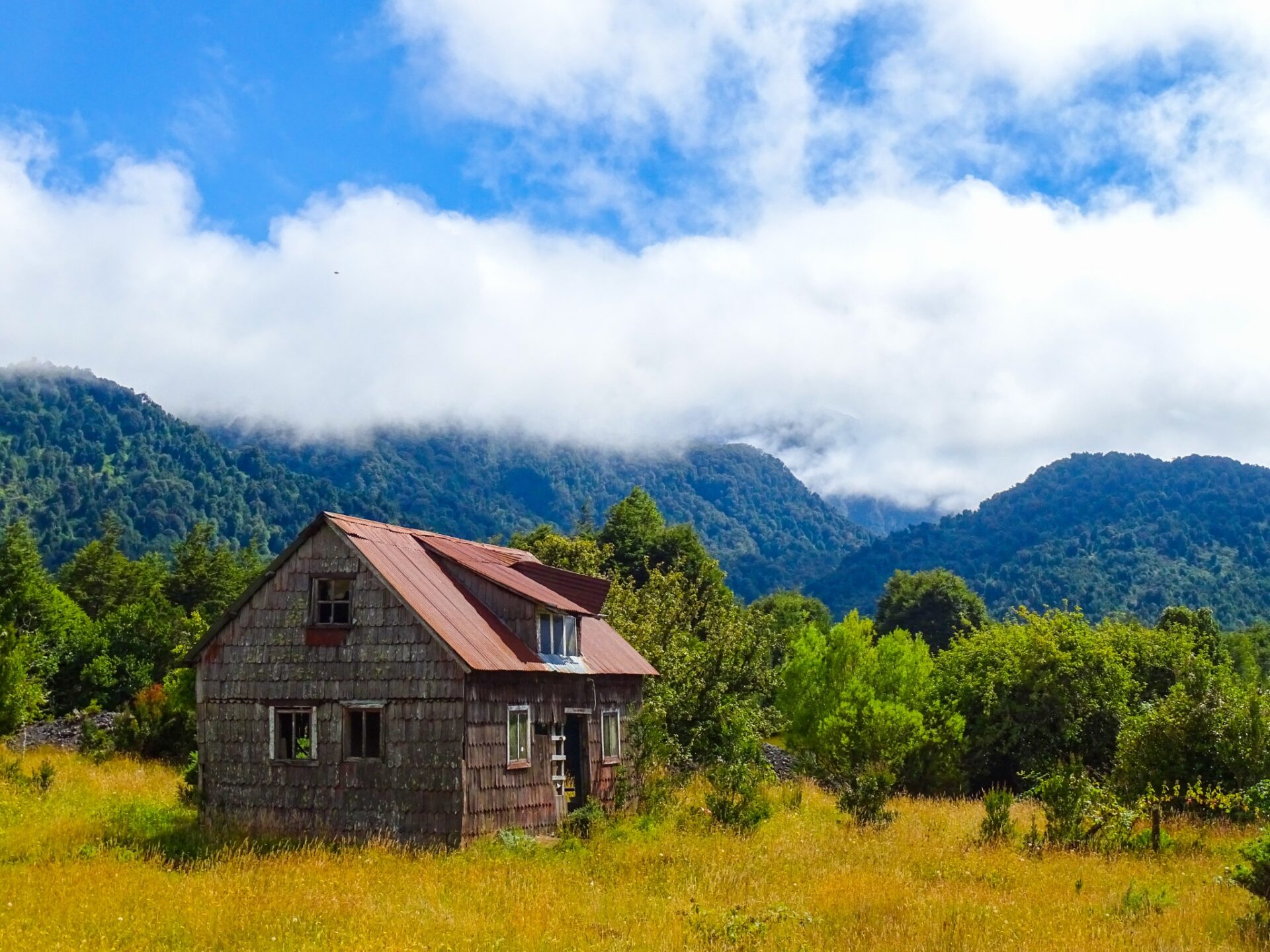 Traditional wooden house surrounded by forest and mountains in southern Chile