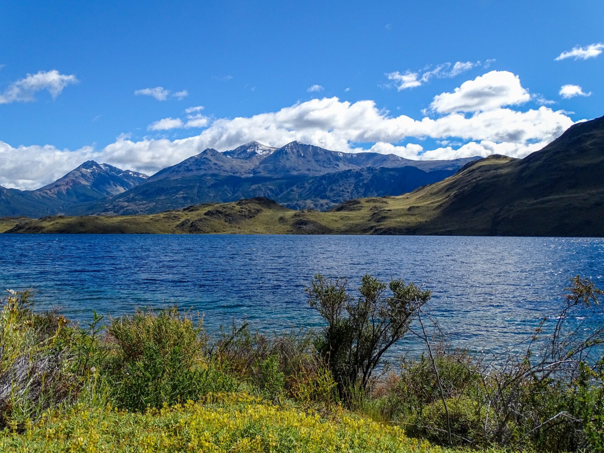 Lago Gutiérrez with mountain peaks and rolling hills beneath a bright Patagonian sky.